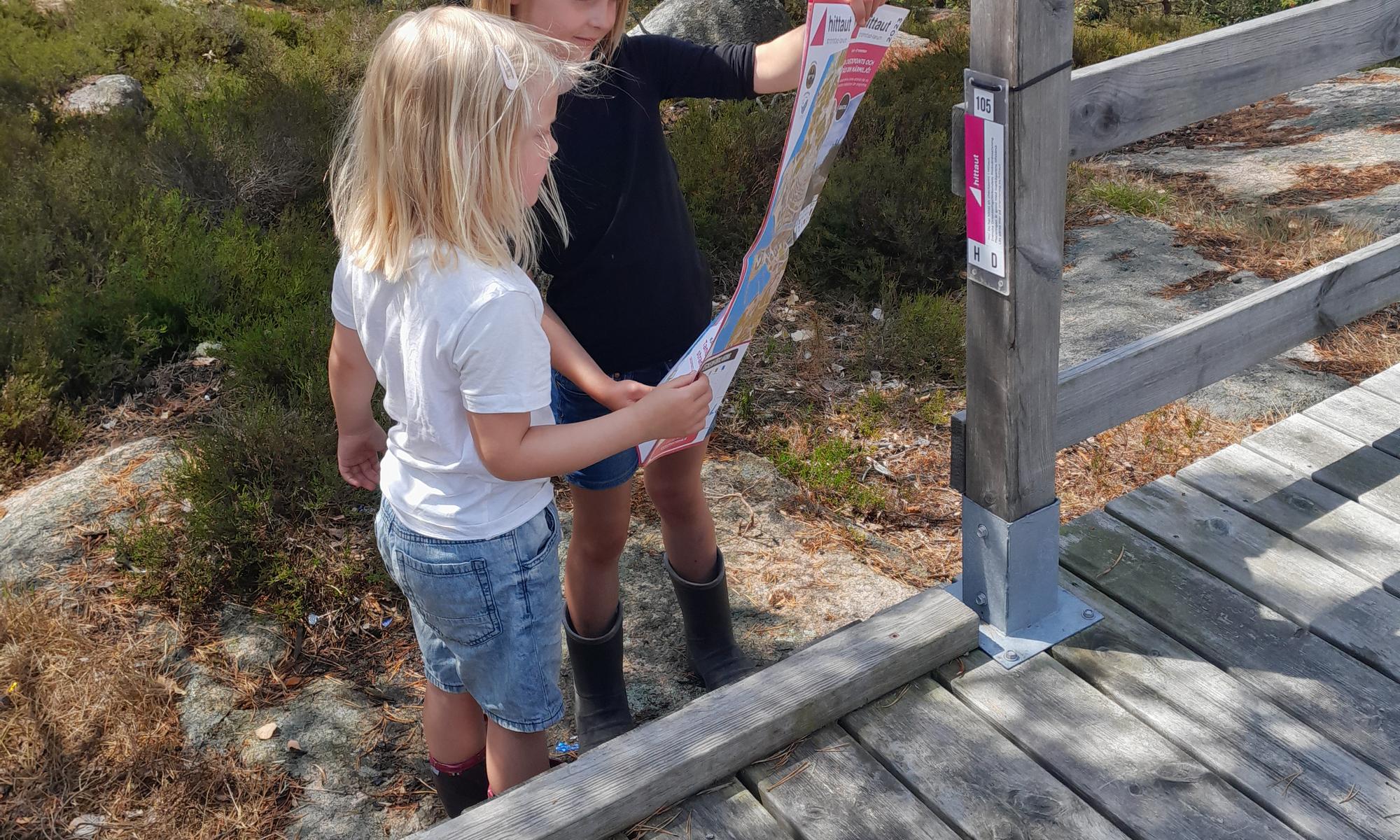 Två barn orienterar och kollar på en karta