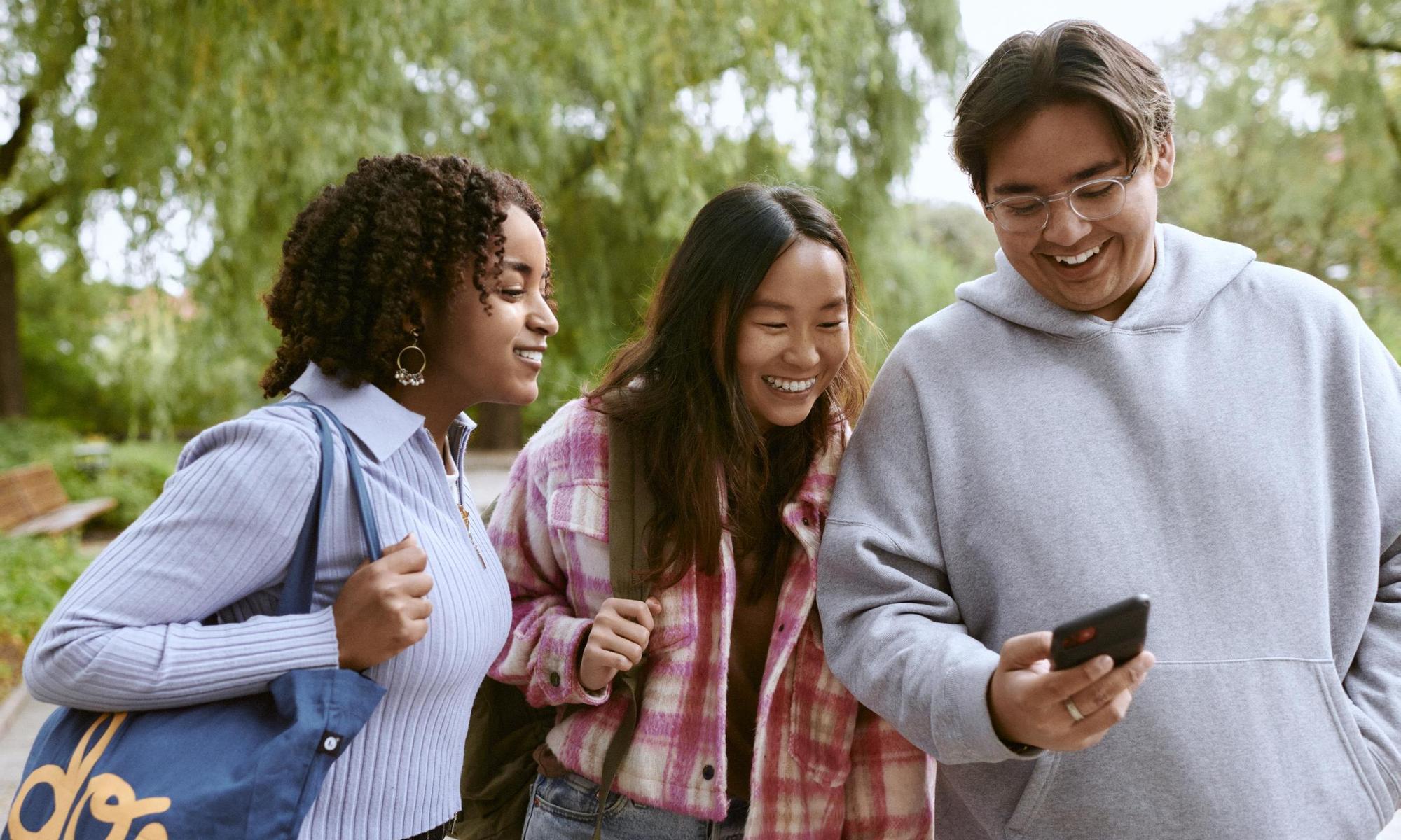 Young adults laughing at something on a mobile