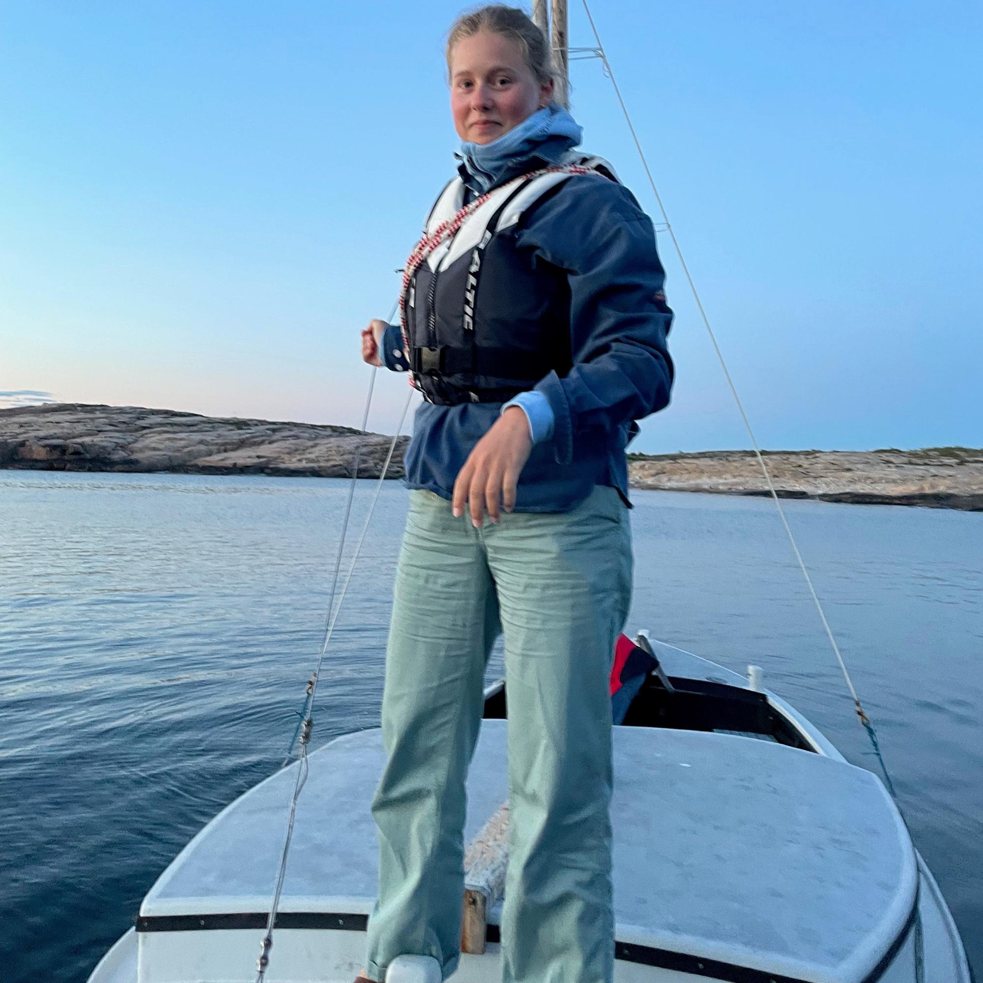 En tjej står på en segelbåt ute på havet