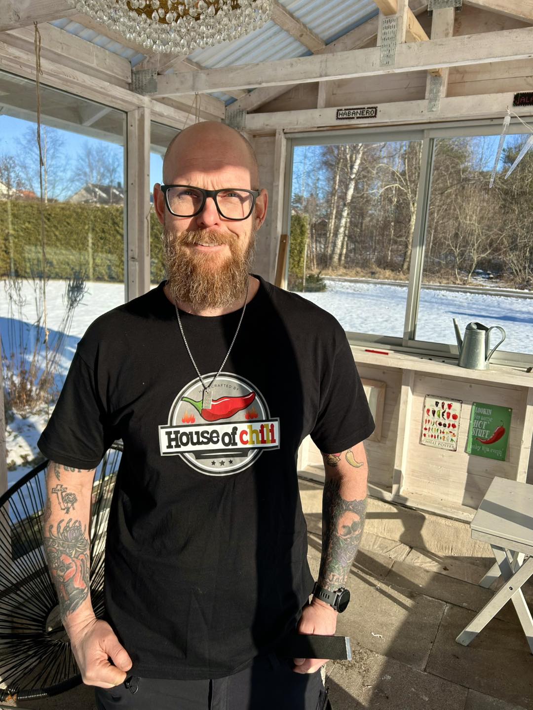 Glen Palm Mattsson står i sitt växthus med en House of Chilli-tröja på sig
