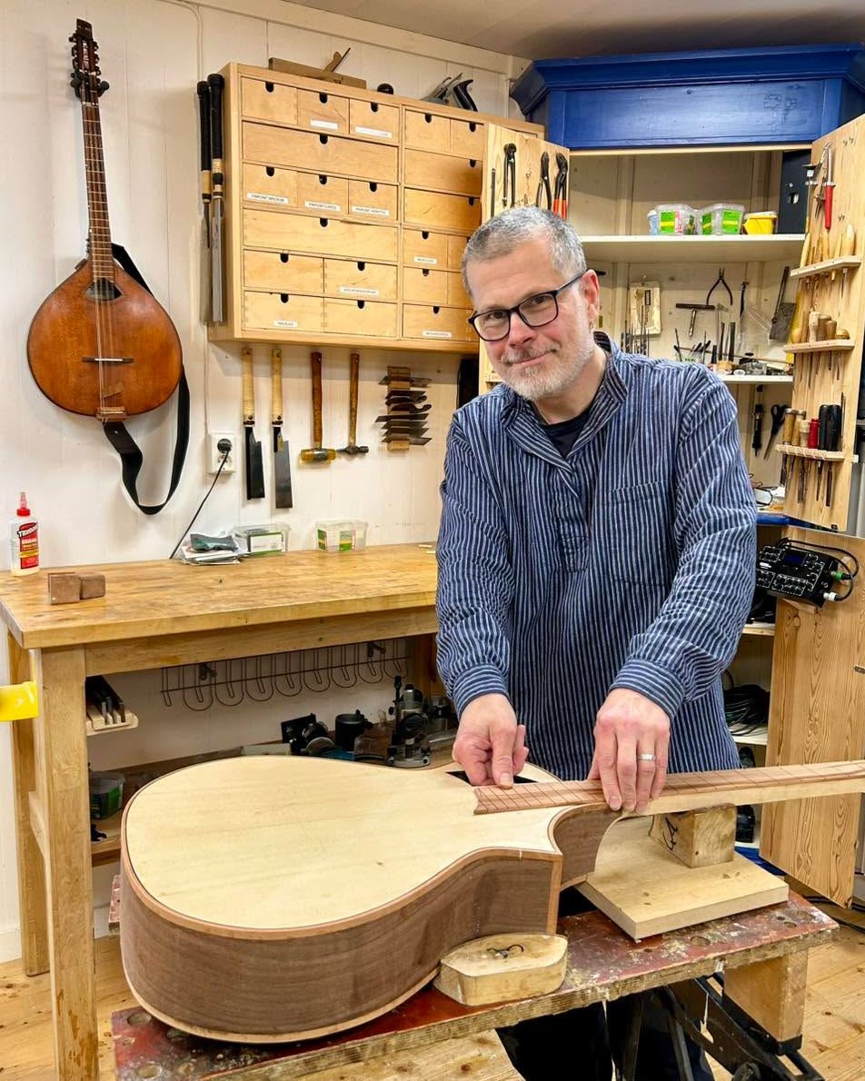 Christer Grell Ådin står i sin verkstad och snickrar på ett instrument