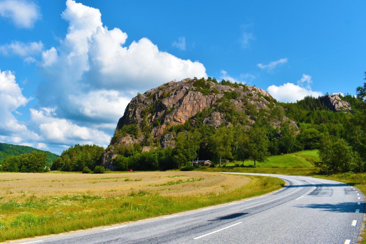 Ett stort berg vid en bilväg och åkermark i Bärfendal