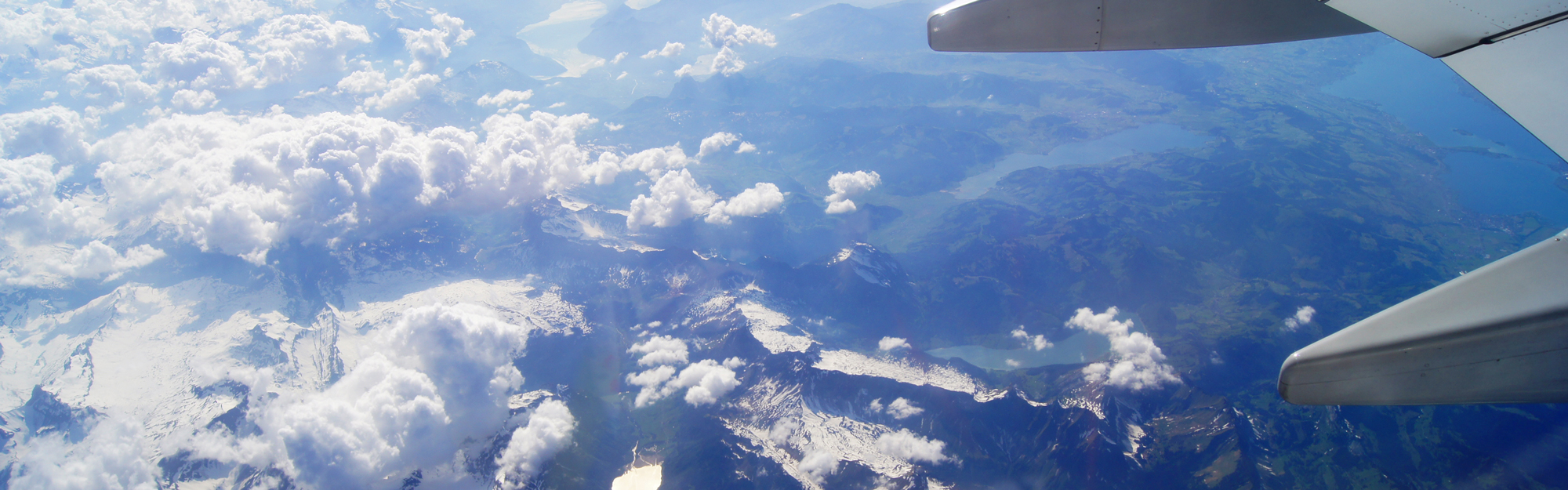 Foto över berg och sjöar från flygplansfönster.