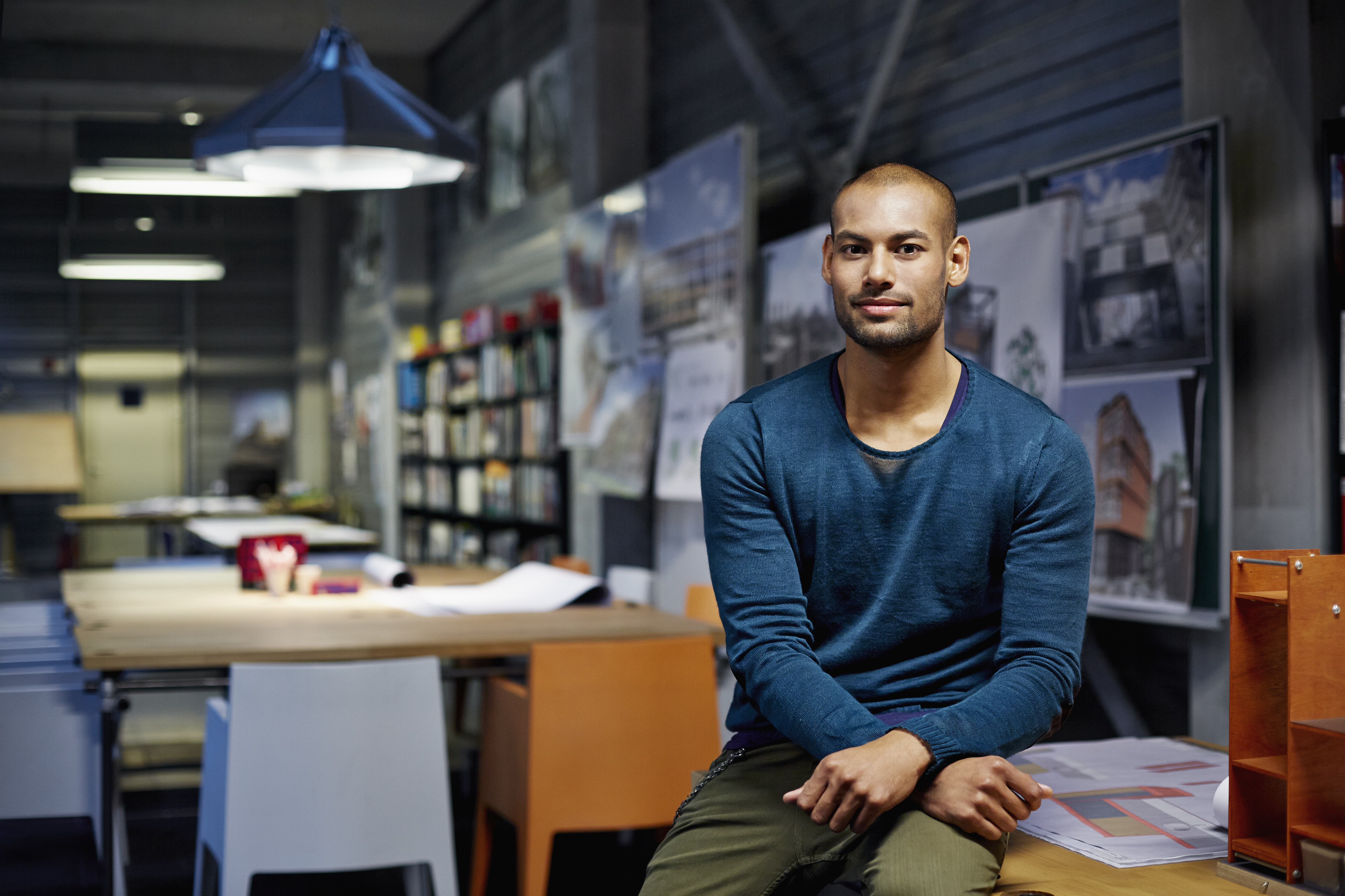 Young man sitting on desk in office