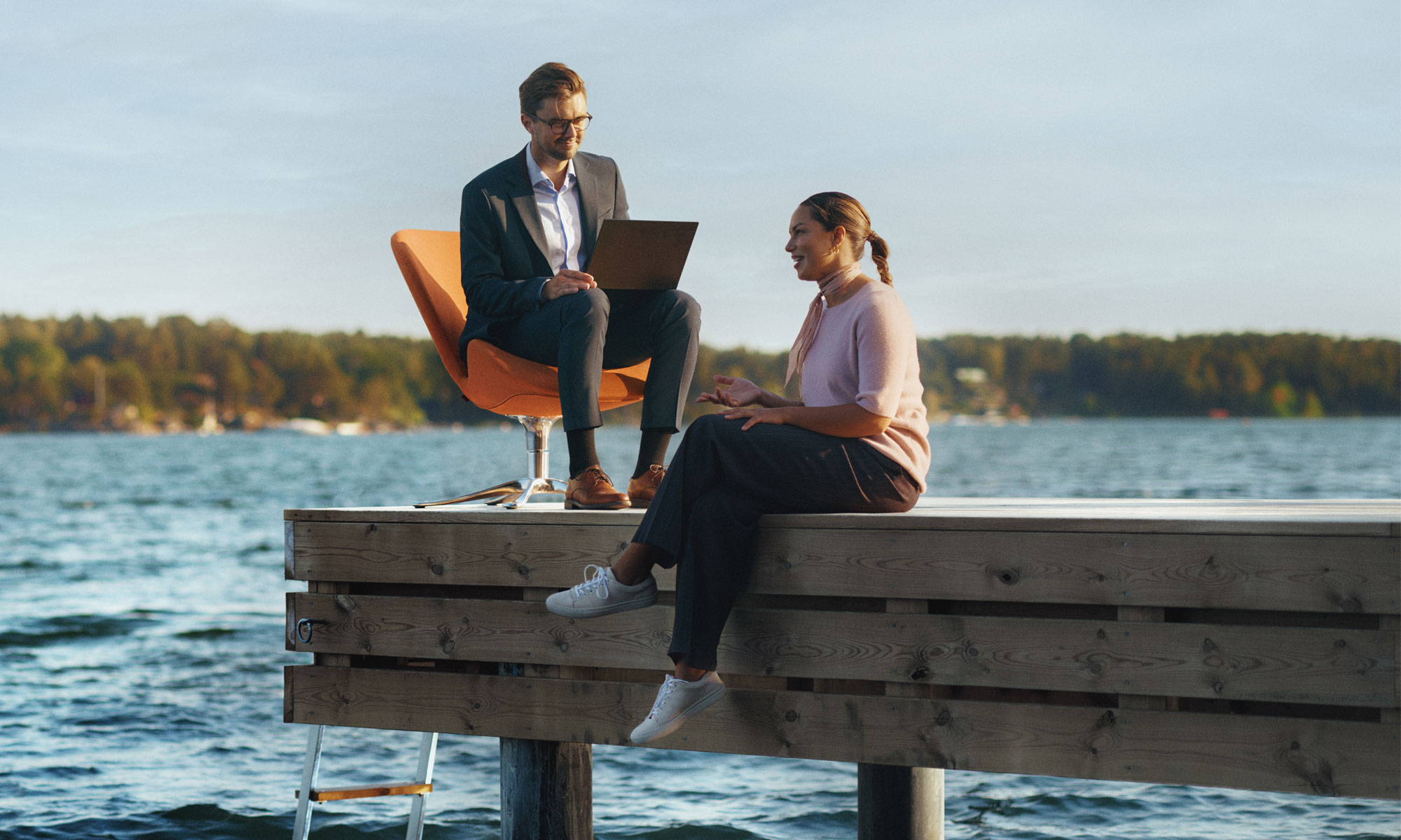 Kundmöte där en man sitter i en orange fotölj på en brygga.